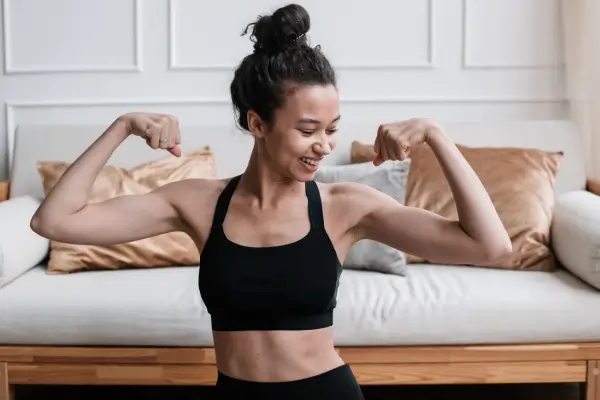 Mulher exibindo os músculos dos braços como símbolo de progresso na musculação, destacando força e determinação.